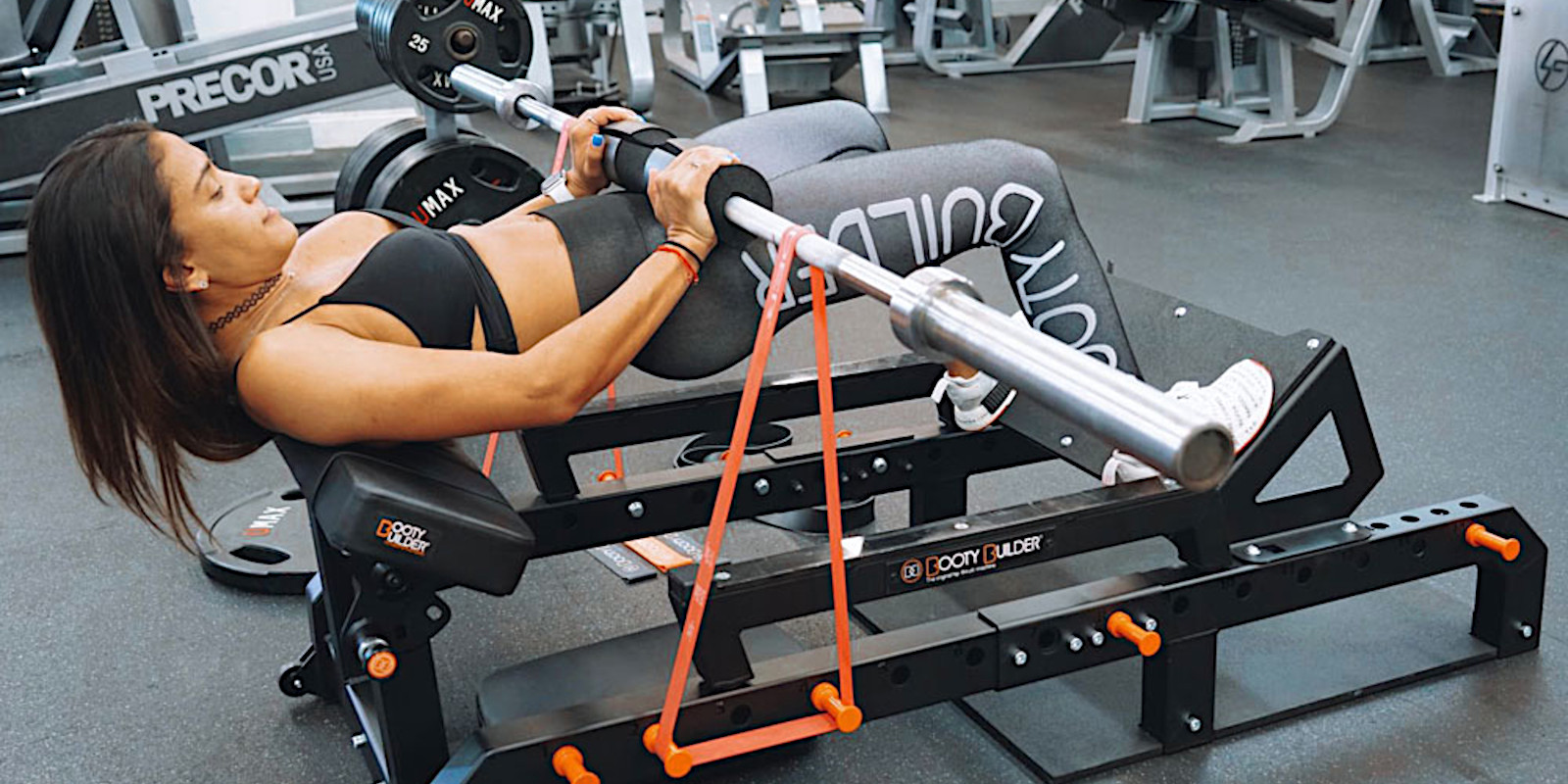a woman using a booty builder machine and bands in the gym