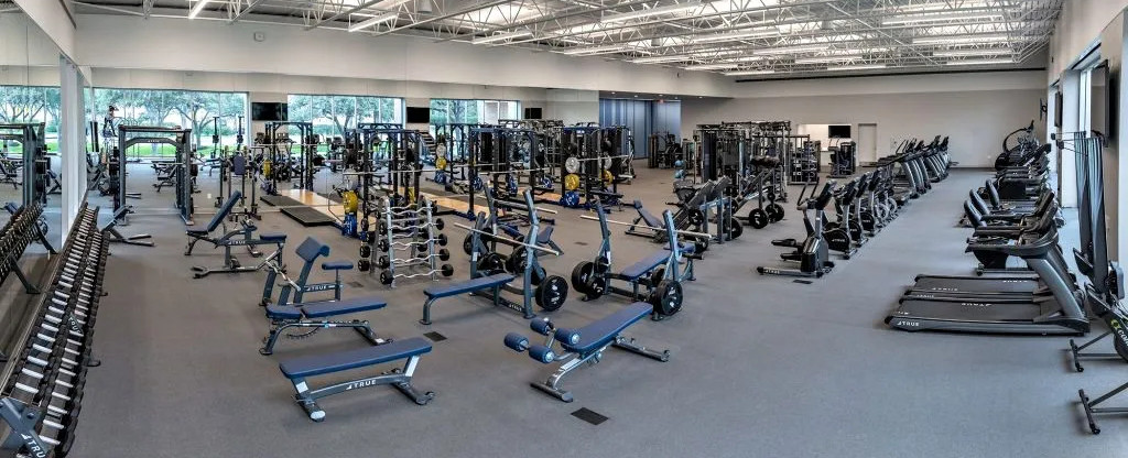 a gym floor that has rows of cardio machines and weight equipment