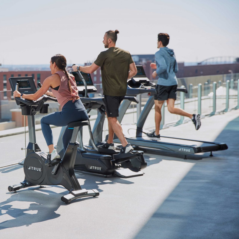 several people exercising on true fitness cardio machines outdoors