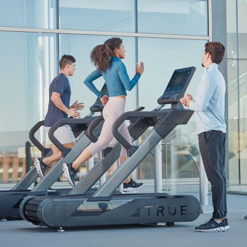 a group of people running on treadmills outdoors